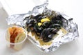 Mussels in wine, butter and garlic, served with bread. Clams in a take-away carton box, on white background, top view.