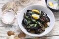 Mussels in wine-butter sauce, sprinkled with parsley, top view. Clams in a bowl, on white wood background.