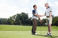 We must play together again soon. Two men shaking hands after a satisfying round of golf.