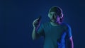 A mustachioed man in white wireless headphones dances and sings into a microphone. Woman in studio on blue background Royalty Free Stock Photo