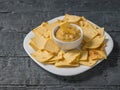 Mustard with Mexican tortilla chips in a white plate on a wooden table. Royalty Free Stock Photo