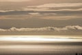 Rows of horizontal cloud above a sunlit sea.