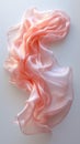 a muted pink silk scarf folded and twisted into an abstract shape that creates a sense of fluidity and movement