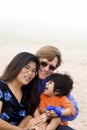 Mutiracial family sitting on beach Royalty Free Stock Photo