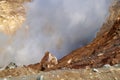 Mutnovsky volcano. Large yellow-gray stone on the edge of the fumarole field. Steaming fumaroles in the crater of the active