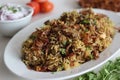 Mutton Biryani prepared with spices layered between mildly spiced ghee rice with a generous sprinkle of caramelized onions and