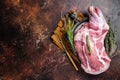 Mutton lamb whole shoulder, raw meat in a steel tray with herbs. Dark background. Top view. Copy space Royalty Free Stock Photo