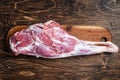 Mutton meat. Raw whole lamb leg thigh on butcher board. Wooden background. Top view