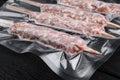 Mutton minced meat on skewers in vacuum pack, on black wooden table background