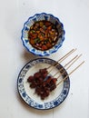 Mutton satays and spicy vegetable sauce on a ceramic plate Royalty Free Stock Photo