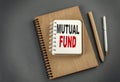 MUTUAL FUND text on notebook with pen and pencil on grey background