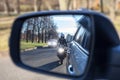 Mutual passing, motorcycle and vehicle with dazzle lighting overtaking the car, view in a side mirror. Improper driving or traffic
