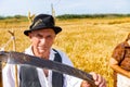 Elderly farmer poses with sharp scythe in his hands. Wheat harvest time Royalty Free Stock Photo