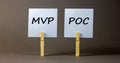 MVP vs POC symbol. Wooden clothespins with white sheets of paper. Words MVP, minimum viable product and POC, proof of concept.