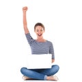 My blog is trending. Studio shot of a young woman sitting cross legged on the floor cheering while using a laptop. Royalty Free Stock Photo