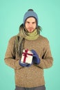 My congratulations. Man bearded handsome wear winter hat scarf gloves hold gift box. Hipster hold christmas gift with