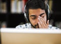 My eyes need a break from this. Closeup shot of a stressed out young man working on a computer while listening to music Royalty Free Stock Photo