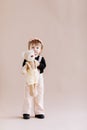 My favorite toy. Cute little 2 years old girl hugging her teddy bear and smiling, decorated beige studio background Royalty Free Stock Photo