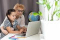 This is my favourite movie. Shot of an adorable little girl using a laptop while sitting at home with her grandmother.