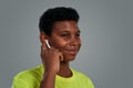 My favourite playlist. Portrait of teenage african boy adjusting wireless earphones and smiling while standing against