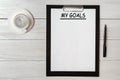 My goals list on note pad paper with pen and coffee on wooden table Royalty Free Stock Photo