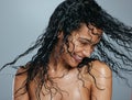 My hair has an attitude of its own. Studio shot of an attractive young woman tossing her wet hair against a grey Royalty Free Stock Photo