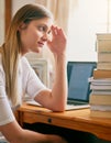 My head hurts from just thinking of all this reading. a young woman looking overwhelmed by the pile of books on her desk Royalty Free Stock Photo