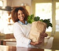 My health is important to me. Portrait of a happy young woman holding a bag full of healthy vegetables at home. Royalty Free Stock Photo