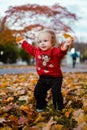 My little daughter plays with autumn leaves in the city park. Cute baby girl playing outdoors. Royalty Free Stock Photo