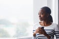 My mid-morning coffee break is always a treat. An optimistic young woman thoughtfully looking out of a window on her Royalty Free Stock Photo