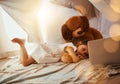 My most favourite movie ever. an adorable little girl at home lying on her bed and watching a movie with her teddybear.