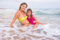 My mother and five year old daughter, sitting in the shallow water at the seaside Royalty Free Stock Photo
