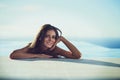 My own bareness is so liberating. Portrait of a beautiful young woman leaning at the edge of a swimming pool on a sunny Royalty Free Stock Photo