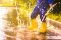 My rubber-booted feet are Bouncing in a puddle. Article about rubber boots. Children`s summer shoes. Puddles after rain. Bad Royalty Free Stock Photo