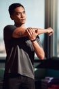 My shoulders have been feeling stiff. Shot of a young man stretching his arms before a workout.