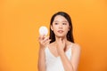 My skin feels great. Shot of a beautiful young woman looking at herself in small mirror over yellow background