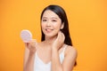 My skin feels great. Shot of a beautiful young woman looking at herself in small mirror over yellow isolated background