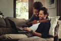 My smile keeper. a happy young couple using a laptop while relaxing on a couch in their living room at home.