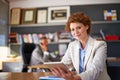 My tablet helps me to be more efficient. a young female assistant using a tablet with her boss working in the background Royalty Free Stock Photo