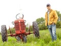 My tractor and I are in this together. Full length portrait of a farmer standing next to his tractor in a field. Royalty Free Stock Photo