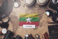 Myanmar Flag Between Traveler`s Accessories on Old Vintage Map. Overhead Shot