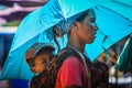 A Myanmar mother holds her son using cloth as a rucksack and spreads a sunshade at Kengtung Market