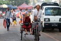 Myanmarese neophyte of monk sitting on the bicycle tricycle taxi with the driver riding in the alleyway of Yangon