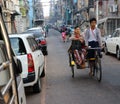 Myanmarese passenger sitting on the bicycle tricycle taxi with the driver riding in the alleyway of Yangon
