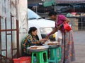 Myanmese woman buying dessert from female street vendor beside the road on the morning at Yangon