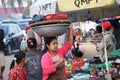 Myanmese woman with thanakha Myanmar powder on her face put big aluminum enameled basin on her head to bring the products to the