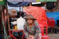 Myanmese woman with thanakha Myanmar powder on her face and wearing conical hat going to sit in a chair