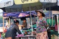 Myanmese woman with thanakha Myanmar powder on her face and wearing conical hat standing in the market