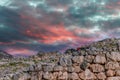 Myceane Greece - Tourists climb the ancient walls that myth claims were built by giants under firey sunset sky - Royalty Free Stock Photo