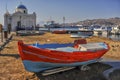 Myconos, Greece, view of the square next to the local church by the sea, where in the foreground an old red fishing boat lies